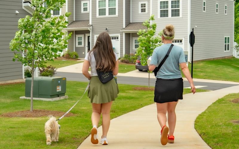 two women walking a dog on a sidewalk